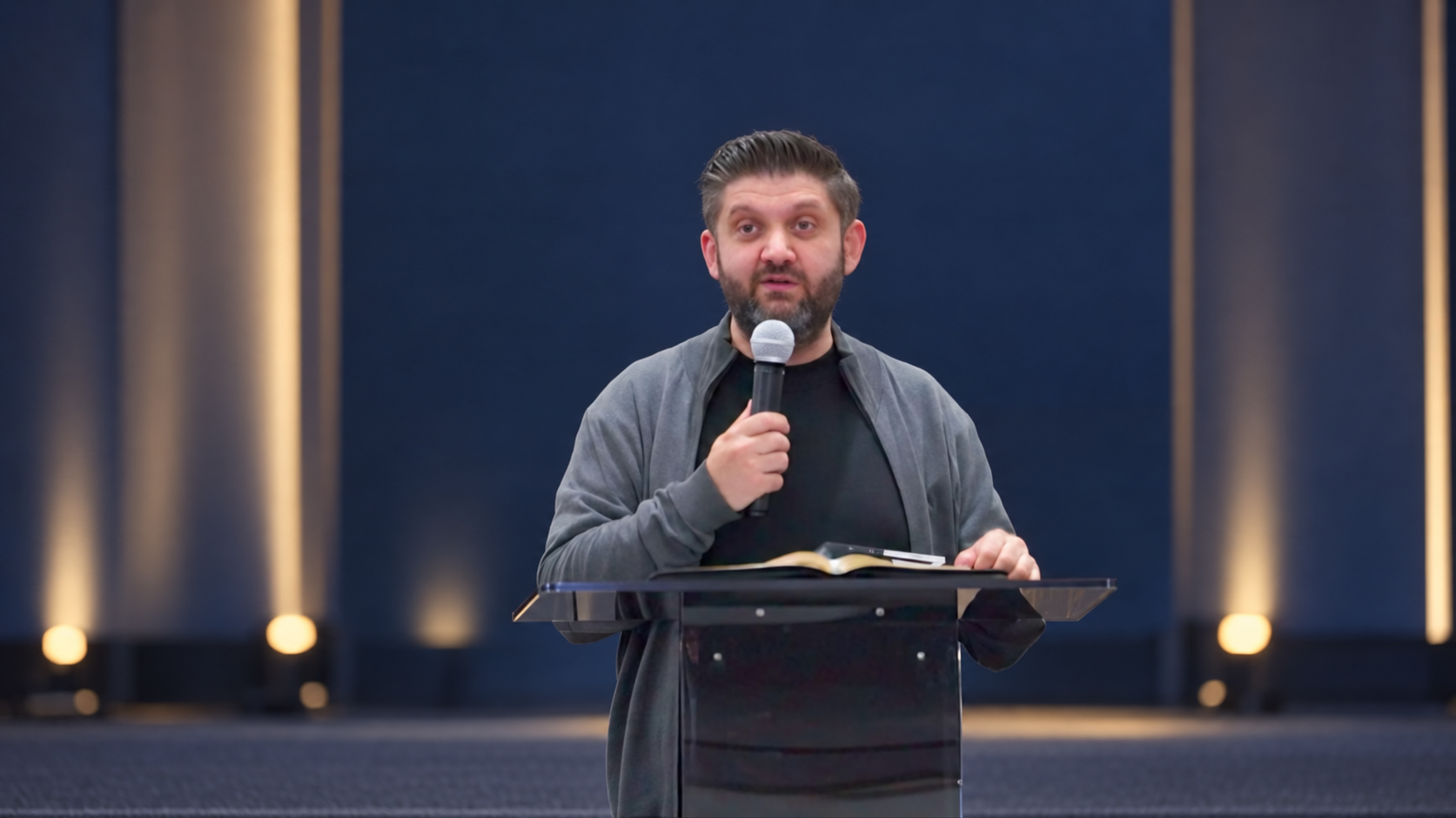 Ioan Caraian vorbind la microfon, cu fundal de scenă editat